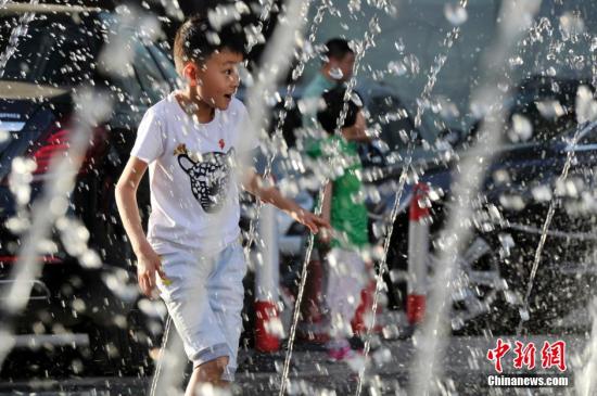 山西太原最高溫36℃,兒童在噴泉周圍戲水消暑。