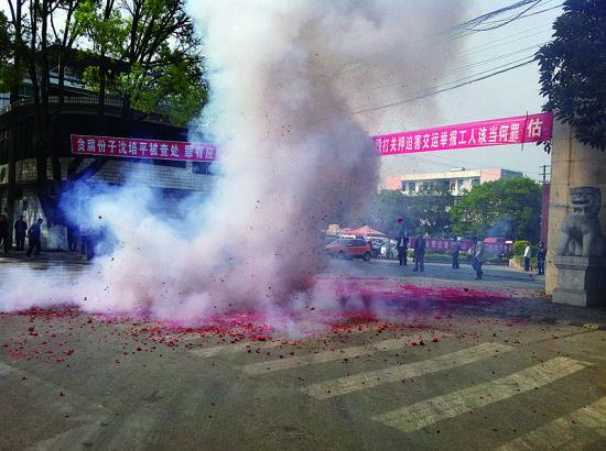 市民在普洱市主干道振興大道的金孔雀交通運(yùn)輸集團(tuán)有限公司門前燃放鞭炮，公司門前掛著“貪腐份子沈培平被查處，罪有應(yīng)得，大快人心?！钡臈l幅