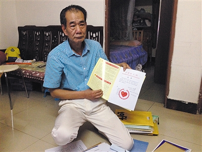 翻出一家網(wǎng)站贈(zèng)予的“中國好人”證書，區(qū)少坤單膝跪在地上，“你看，我是中國好人啊?！?范春旭 攝