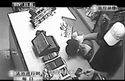 戴帽男子一手掐住加油站營業(yè)員，一手持發(fā)令槍指向另一營業(yè)員，要求“把錢給我裝起來”。