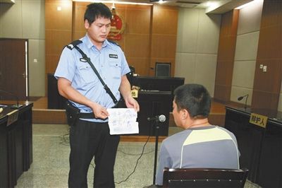 昨日庭審中，法警向趙某出示其扎完車胎后所留辱罵公司的紙條。通訊員 李秀文 攝