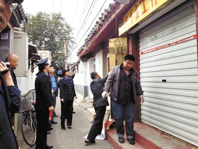 執(zhí)法人員拆除胡同里一家店面未經(jīng)審批的招牌。