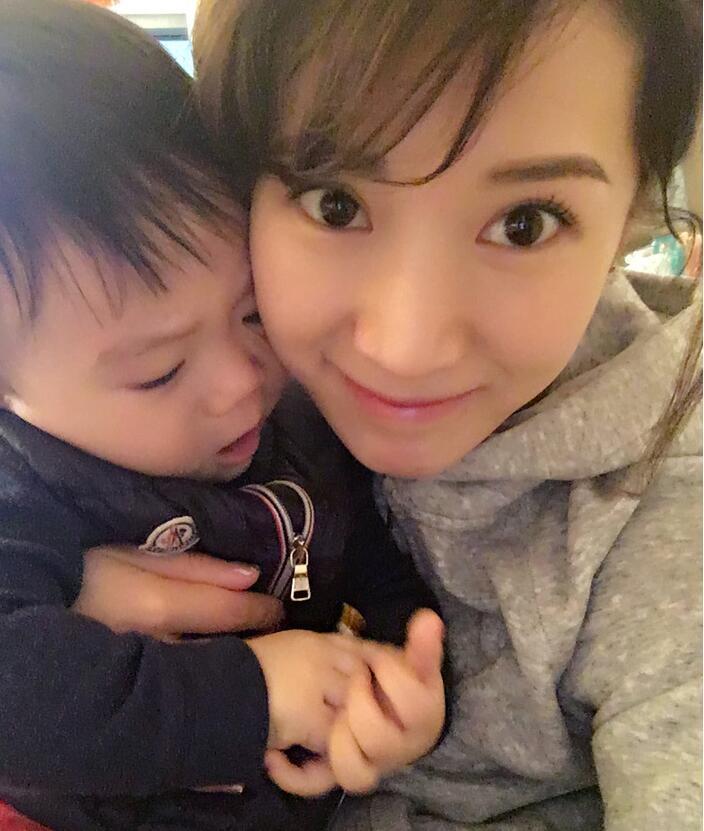 照片中李念狂吻兒子，小寶貝自顧自地玩著。