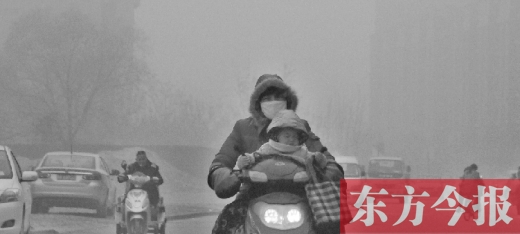 12月8日，鄭州市未來路上，一位市民帶著孩子在霧中騎行