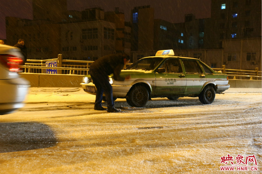 一位出租車司機(jī)在車輪前灑上雪，希望能增加輪胎的摩擦力。