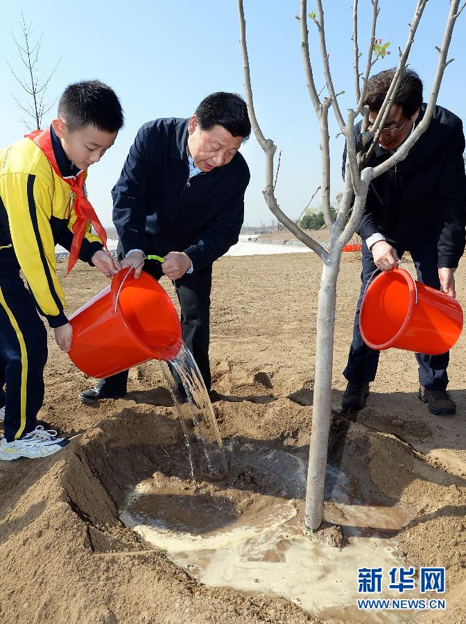 這是習(xí)近平同大家一起給剛栽下的樹苗澆水。