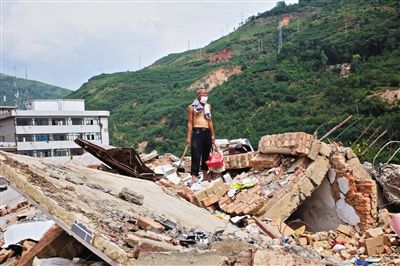 8月9日,龍頭山鎮(zhèn),一位老者在自家房屋廢墟上尋找家當(dāng)。