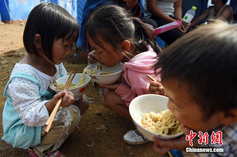 2014年8月6日，云南魯?shù)辇堫^山災(zāi)區(qū)，兒童在帳篷外吃飯。
