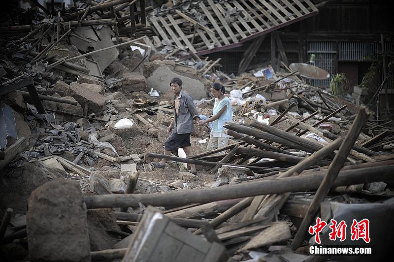 2014年8月5日，云南昭通龍頭山鎮(zhèn)老街，一對(duì)夫妻從居住房屋的廢墟中走過。
