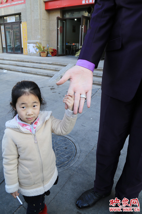 巨人“張歡”牽著一名漂亮的小女孩，兩人的手大小對比非常明顯。