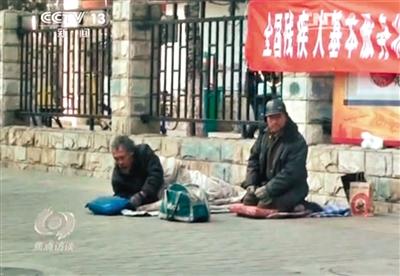 工人體育場北路，兩位乞討者路邊乞討，并輪流扮成“病人”（躺地者）。 央視截圖